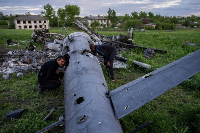Two men study the remains of a Russian missile in the village of Mala Rohan, Kharkiv Oblast, Defense Express