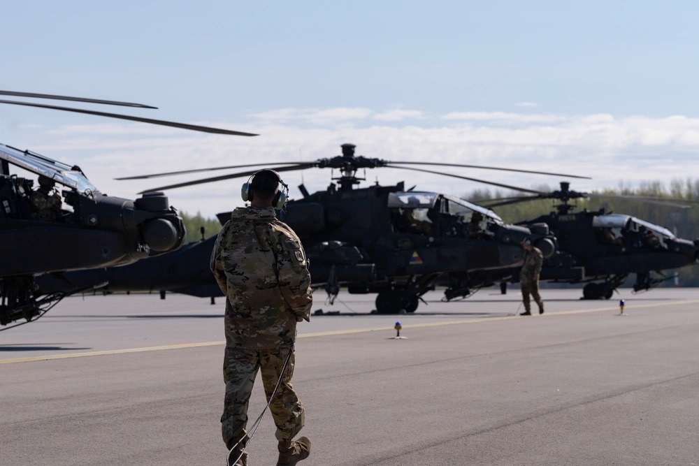 Illustrative photo: a U.S. Army soldier walks past a line of AH-64D Apache helicopters in Lielvārde, Latvia, May 2, 2025 / Defense Express / Drones, Training, and Unity: Key Messages of the Kyiv Security Forum (Live Updates)