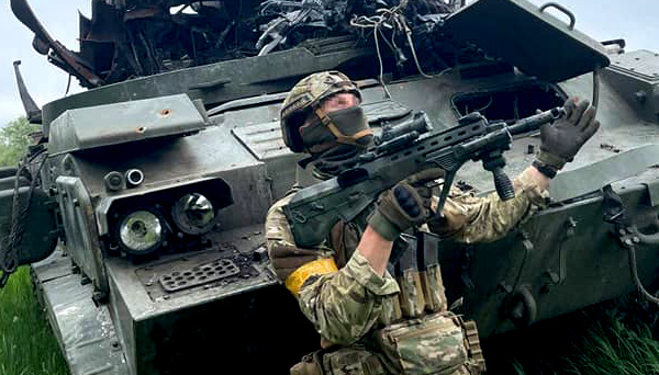 Ukraine's fighter posing in front of destroyed russia's vehicle / Photo credit: General Staff in Ukraine, Defense Express