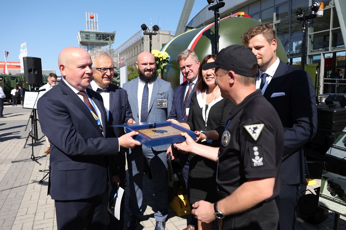 Ukrainian Police Pyrotechnics Get Valuable Gift from Poles on MSPO 2023, Wiktoria Explosion-Proof Container, Symbolic handover of the explosion-proof container to the Ukrainian side. Wiktoria explosion-proof container on Zasław chassis in the background, Defense Express