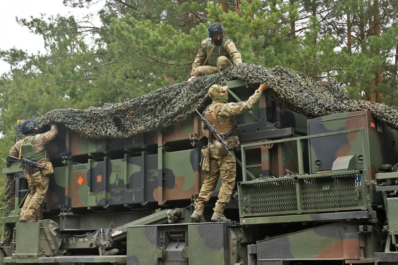 Ukrainian soldiers disguise the Patriot system at an unknown location in Ukraine