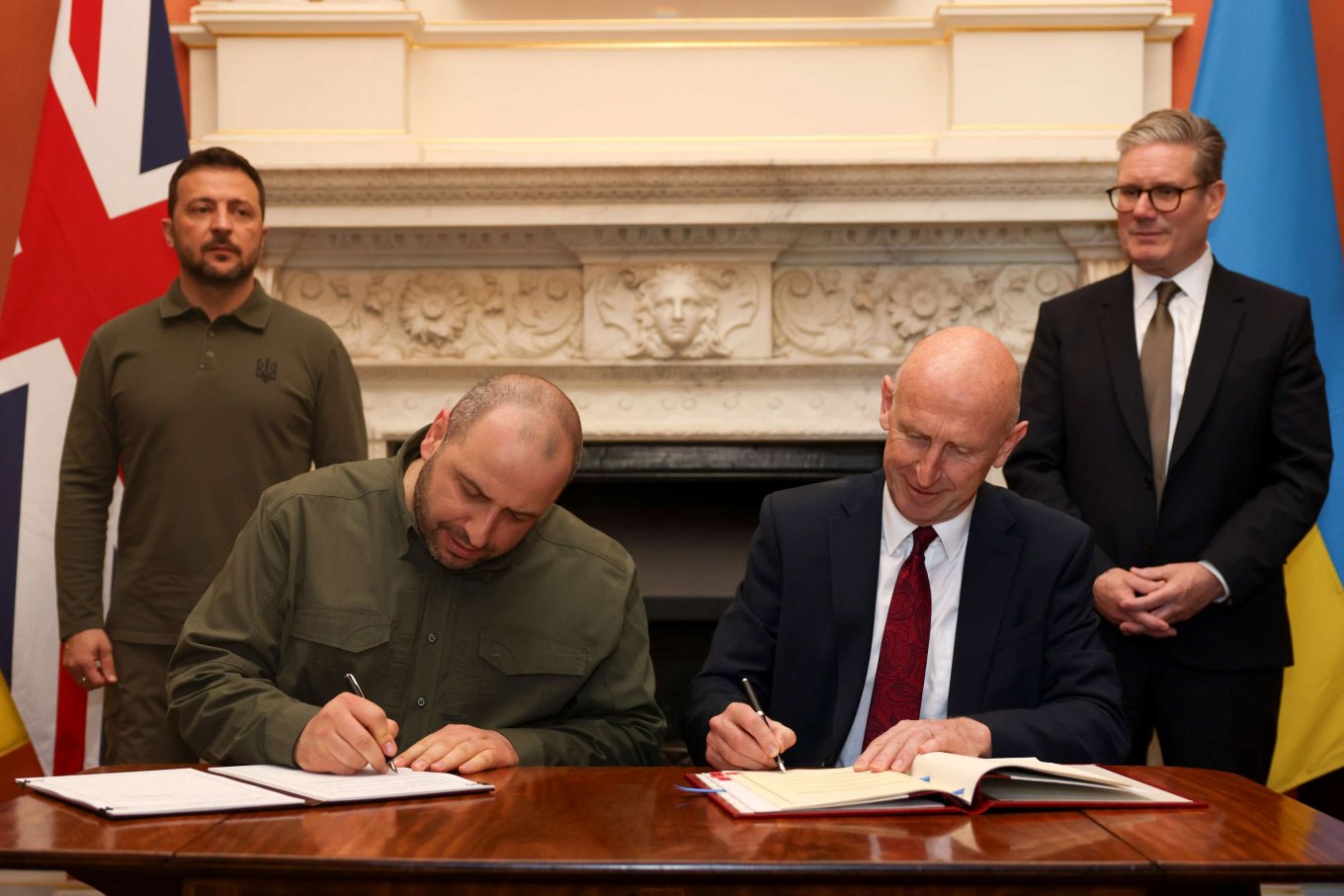 Rustem Umerov (left) and John Healey (right) sign the bilateral agreement on a GBP 2 billion loan for Ukraine's defense. Ukrainian President Zelenskyi and British PM Keir Starmer stand beside them / Defense Express / Which Weapon Projects Will Be Financed With UK's £2 Billion of Ukraine Aid