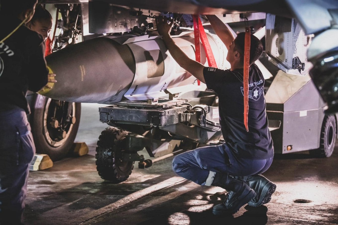 Israeli Air Force technical personnel install 2,000-pound BLU-109/MK 84 aerial bomb equipped with JDAM guidance kit aboard a fighter jet
