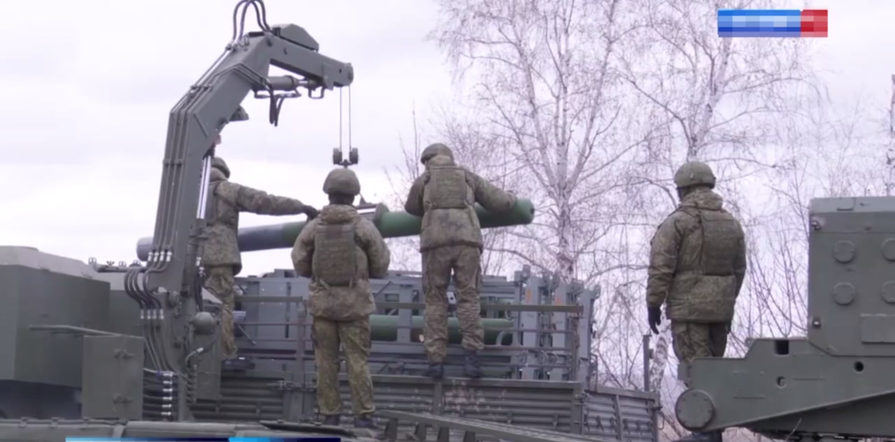 russian soldiers take the rockets from the TMZ-T and load them into the TOS-1A