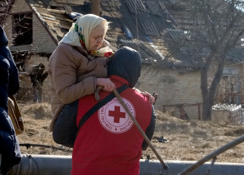 A Red Cross worker carries an elderly women during evacuation in Irpin, some 25 km (16 miles) northwest of Kyiv, Friday, March 11, 2022, Defense Express