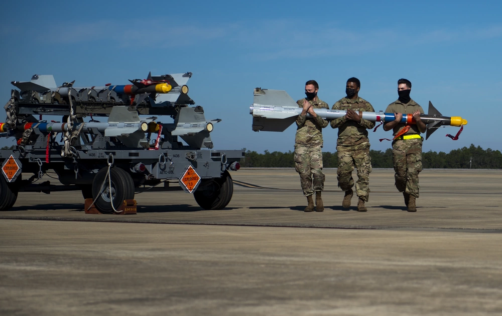 U.S. airmen carry an AIM-9 missile to an F-22 Raptor for a live-fire evaluation exercise