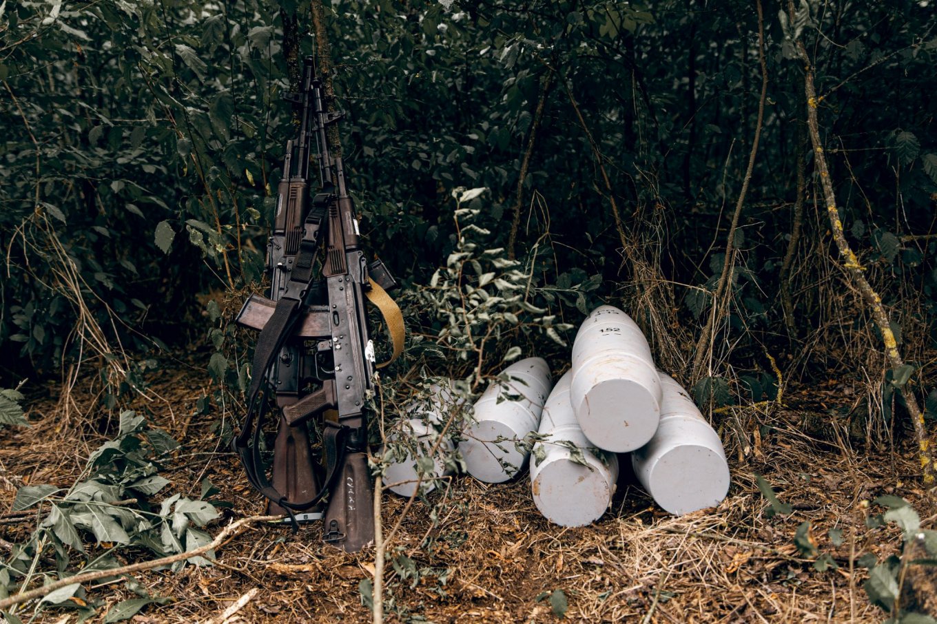 Illustrative photo: a pair of rifles next to a pile of 152mm artillery shells