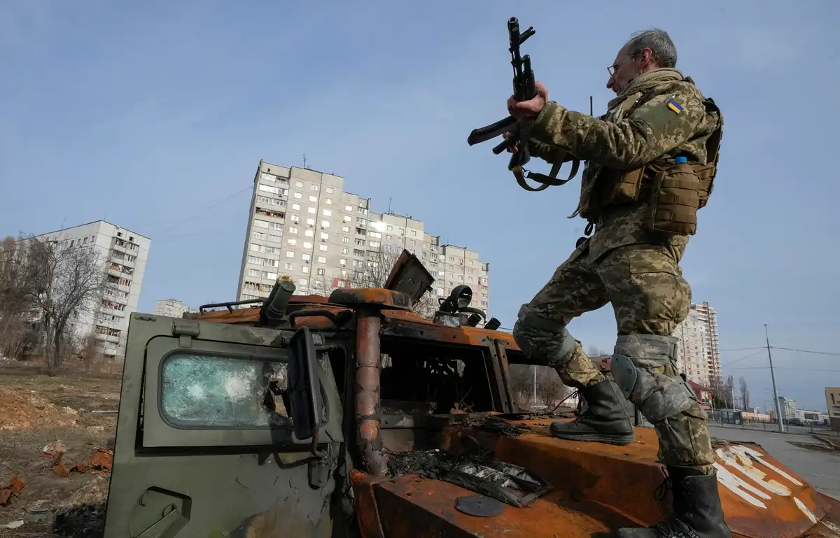 A Ukrainian soldier stands a top a destroyed Russian APC, March 26, 2022. (AP Photo/Efrem Lukatsky)