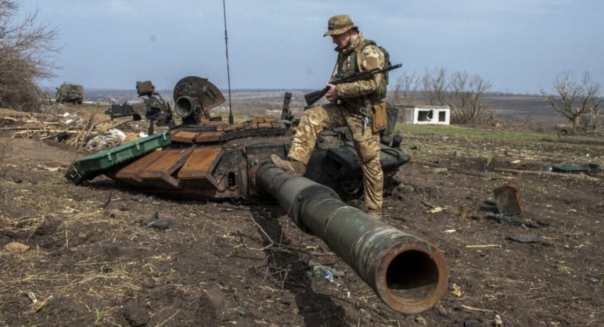 Ukrainian warrior is standing on russian tank that was destroyed in Ukraine / Illustrative photo