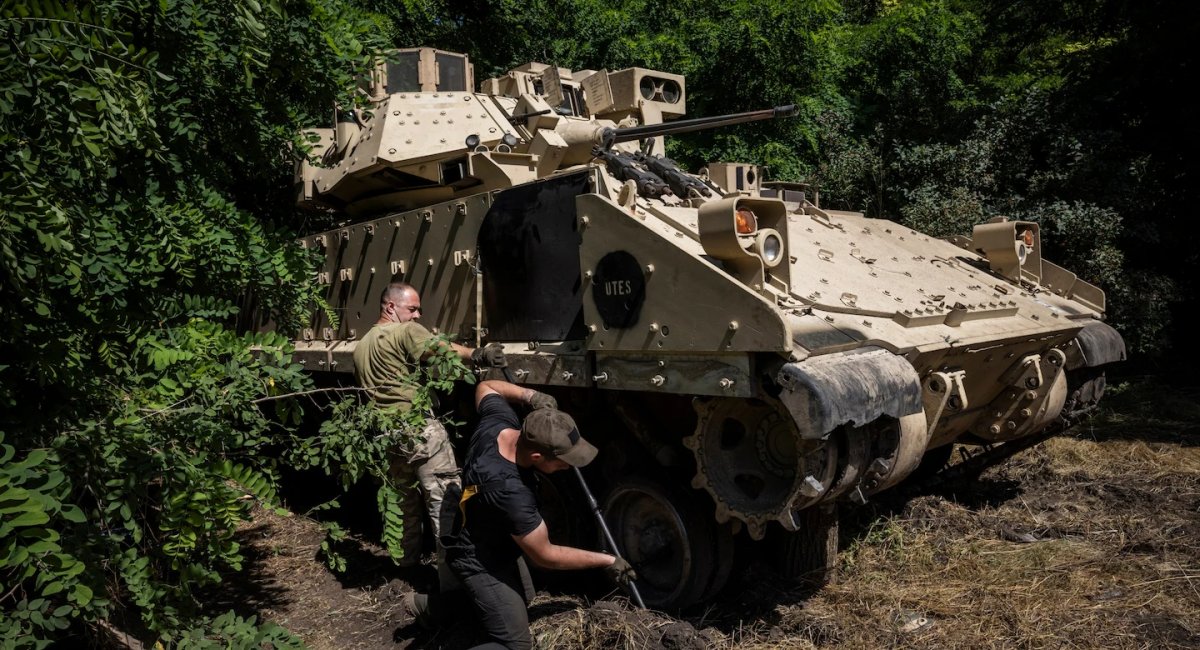 Troops work on a Bradley's tracks at the woods-concealed workshop. (Ed Ram for The Washington Post)